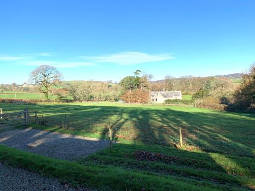 a large grassy field with a house in the background at Luxury Shepherds Hut with Superb Views & Fire Pit & walking distance to a superb Gastro Pub in Lamerton