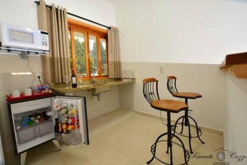 a kitchen with two bar stools and a refrigerator at Hotel Villa Greenberg in Monte Verde