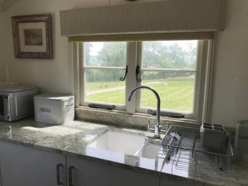 a kitchen counter with a sink and a window at Stunning Shepherds Hut with Superb Views & Fire Pit near a Superb Gastro Pub in Lamerton