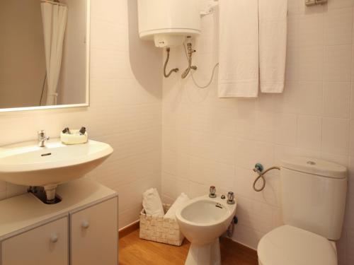 a white bathroom with a toilet and a sink at Casa adosada en Platja de Pals by Apartaments Golf in Pals
