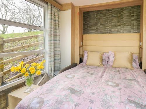 a bedroom with a pink bed and a window at The Fox Den in Rhayader