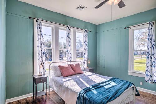 a bedroom with a bed with blue walls and windows at Lake Charles Cottage with Fireplace and Yard! in Lake Charles