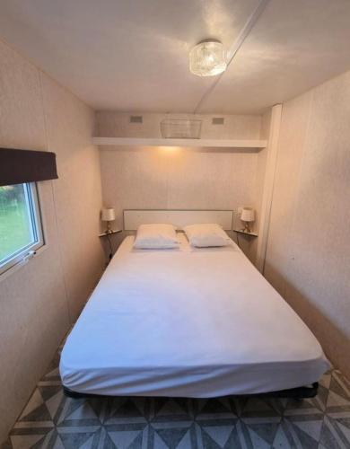 une chambre avec un grand lit blanc avec deux oreillers dans l'établissement La belle Perrochoise 2 mobilhome, à La Cotinière
