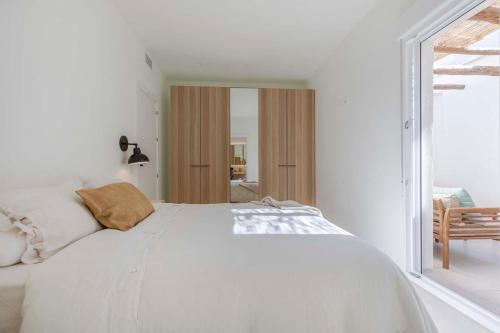 Cama blanca en habitación blanca con ventana en Agradable casa con patio interior., en Molina de Segura