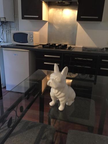 Victor Hugo 2G et sa pizza offerte في أوريلاك: تمثال كلب أبيض صغير جالس على طاولة في مطبخ