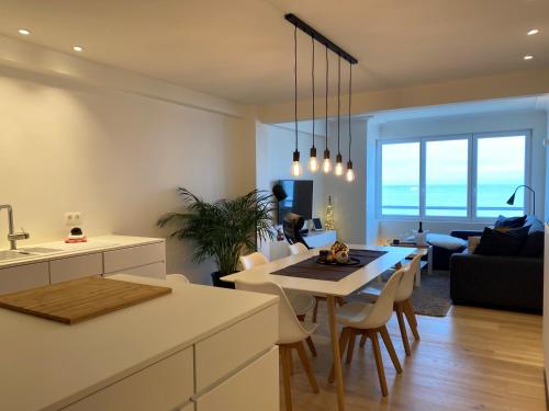 een keuken en een woonkamer met een tafel en stoelen bij OSKAR luxe appartement op zeedijk met zeezicht in Oostende