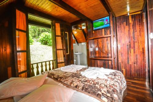 um quarto com uma cama e uma TV na parede em Hotel Fazenda Floresta Negra em Monte Verde