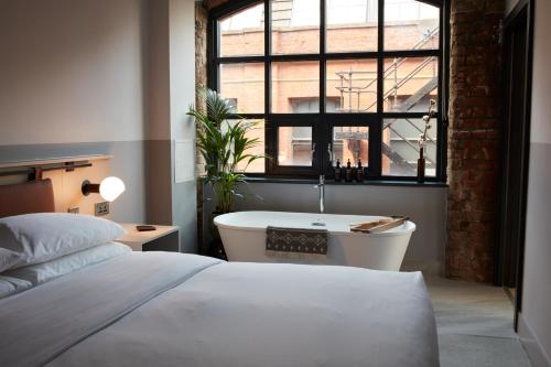 a bedroom with a bed and a bath tub and a window at Leven Manchester in Manchester