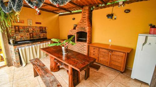 a kitchen with a wooden table and a fireplace at Casa dos Franceses Ilha Grande in Abraão