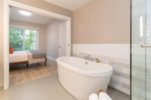 a white bathroom with a tub and a bedroom at Coffee With A View, Brand New One Bedroom At Sooke Harbour in Sooke
