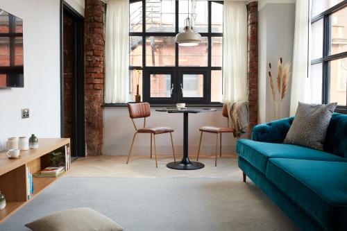 a living room with a blue couch and a table at Leven Manchester in Manchester