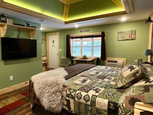 een slaapkamer met een bed en een flatscreen-tv bij Moosewood Inn in Saint Ignace