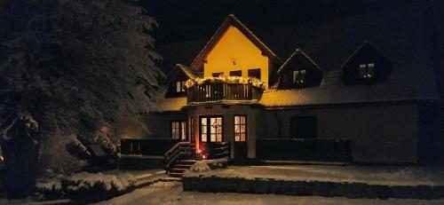 a house with a balcony in the snow at night at Naruby Ubytování in Mařov u Úpice