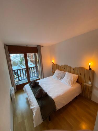 a bedroom with a large white bed with a window at NÓRDIKA - Appartement chaleureux 10' des pistes in El Tarter