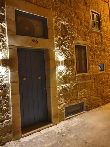 a building with a blue door on the side of it at B&S Accommodation Renovated 18 Century House of Character Ghaxaq, Malta in Hal Ghaxiak