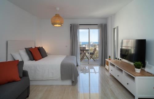 a bedroom with a bed and a couch and a television at Júpiter Suites by Kaarina in Benalmádena