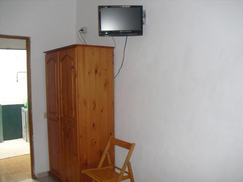 un televisor sentado en la parte superior de una pared junto a un armario de madera en Pension El Guanche, en La Frontera