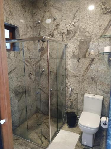 a bathroom with a glass shower with a toilet at Suites na Casa da Praia in Ilhabela