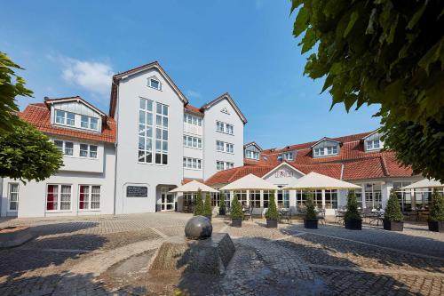 een groot wit gebouw met een standbeeld ervoor bij nestor Hotel Neckarsulm in Neckarsulm