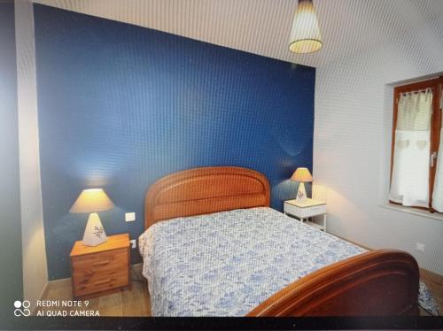 1 dormitorio con una pared azul, 1 cama y 2 lámparas en Agréable T2 avec petite cour privative, en La Bourboule
