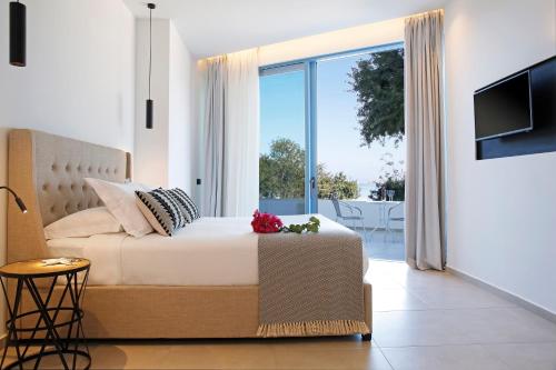 a bedroom with a bed and a sliding glass door at Oasis Beach Hotel in Skala