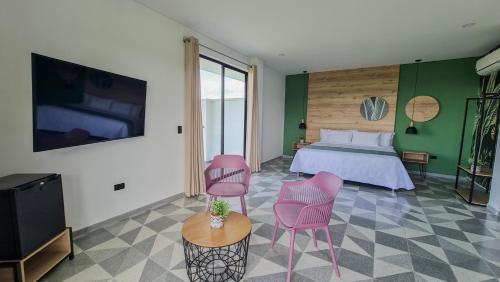 a bedroom with a bed and two pink chairs at Hotel Arbóreo Doradal in Doradal