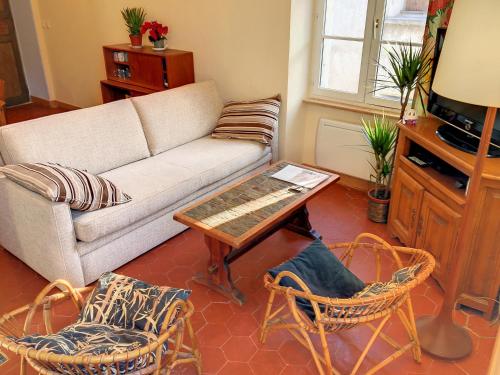 a living room with a couch and a table and chairs at Résidence Verdi - Appartements meublés en centre ville in Bédarieux