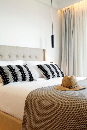 a bed with black and white pillows and a hat on it at Oasis Beach Hotel in Skala