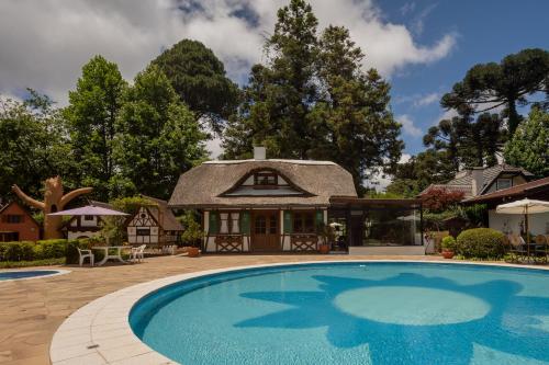 uma casa com piscina em frente a uma casa em Hotel Ritta Höppner em Gramado