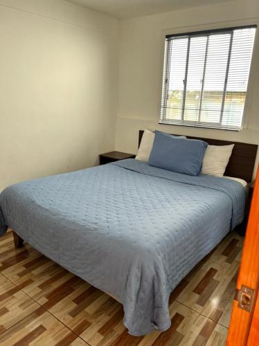 a bedroom with a large bed with blue sheets and a window at Cabañas Costatour Quintero in Quintero