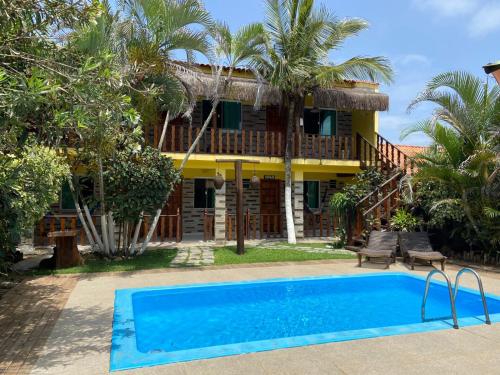 a house with a swimming pool in front of it at Pousada Potigua in Maricá