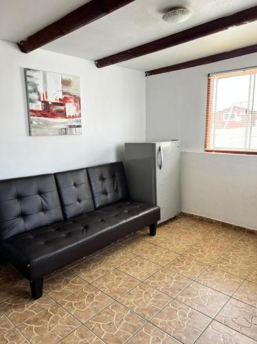 a black leather couch in a room with a refrigerator at Cabañas Costatour Quintero in Quintero