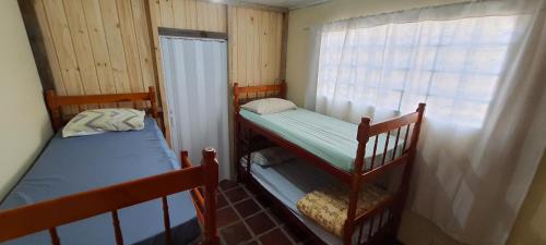 two bunk beds in a small room with a window at Hostel Caxias do Sul in Caxias do Sul