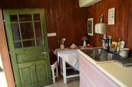 a kitchen with a green door next to a table at Őrálló Szer in Őriszentpéter