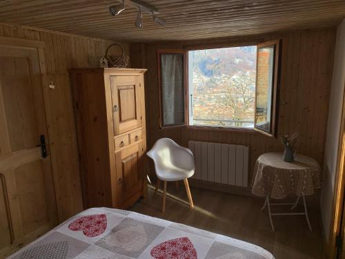 a bedroom with a bed and a chair and a window at Chalet avec terrasse et vue sur le Mt-Blanc in Sallanches