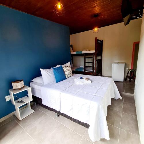a bedroom with a large bed with a blue wall at Pousada Doce Mar in Guarda do Embaú