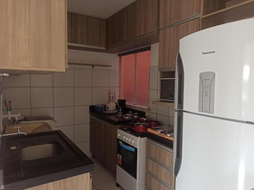 a kitchen with a white refrigerator and a stove at Apto dois quartos, cozinha equipada, portaria 24 h, área de lazer in Imperatriz