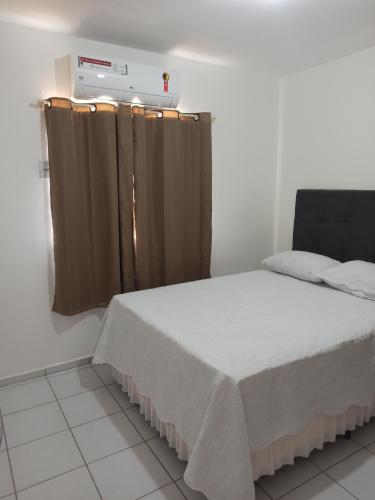 een slaapkamer met een bed en een raam met gordijnen bij Apto dois quartos, cozinha equipada, portaria 24 h, área de lazer in Imperatriz