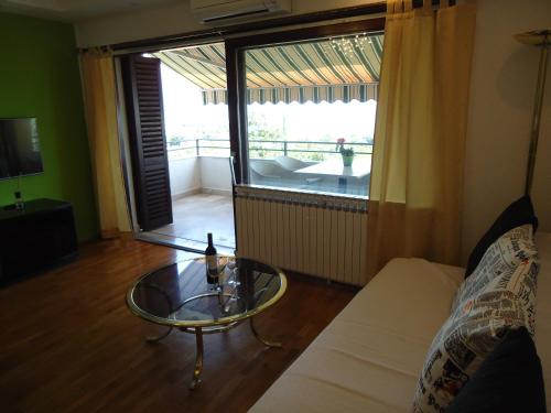 a living room with a glass coffee table and a balcony at Villa Kubo in Lovran