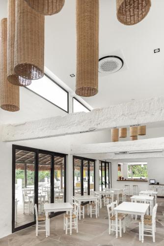 a restaurant with white tables and chairs and windows at Miradouro de São Sebastião in São Sebastião