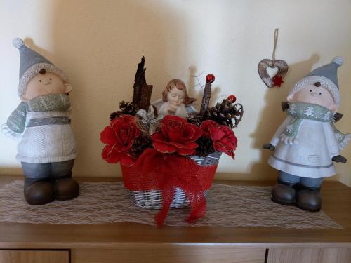three dolls and a basket of flowers on a shelf at Appartement Fritzenwallner in Wagrain