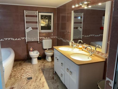 a bathroom with two sinks and a tub and a toilet at Casa Marinela in Baile Felix