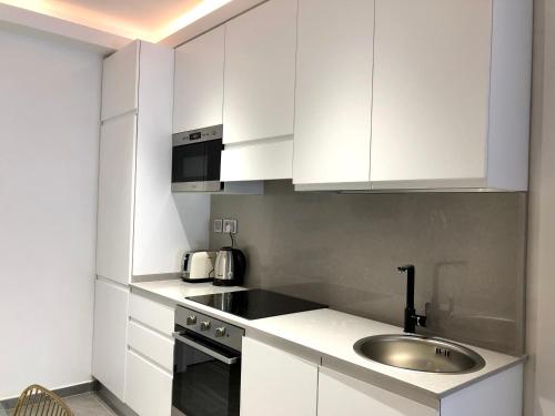 una cocina con armarios blancos y fregadero en Apartments by Sliema promenade and beach, en Sliema