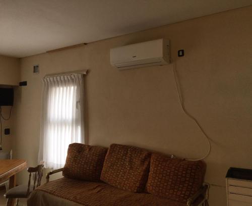 a living room with a couch and a air conditioner on the wall at Alquiler Temporario Olavarría in Olavarría