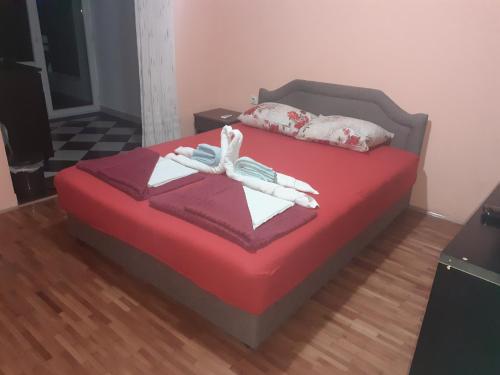 a bedroom with a red bed with two white gloves at Studios Milošev in Bar