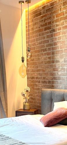a bedroom with a brick wall with a bed and two lights at Casa Checca e Casa Maria appartamenti per vacanze in Caprarola
