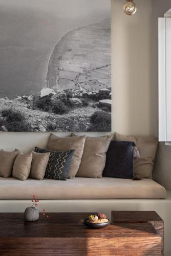 a living room with a couch with a painting on the wall at West East Suites in Imerovigli
