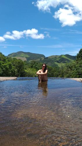 a woman sitting in a tub in a body of water at Pousada Caminho dos Ipês in Bocaina de Minas