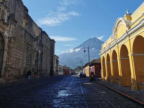 a cobblestone street with buildings and a mountain in the background at Huellas Hostal Antigua in Antigua Guatemala