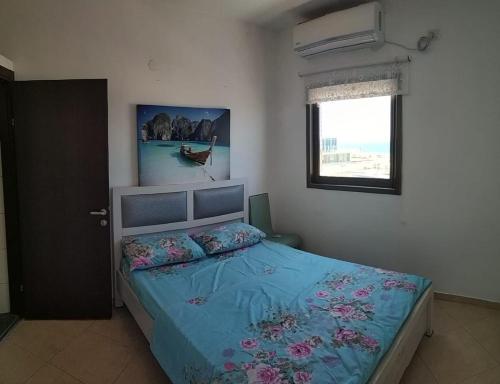 a bedroom with a bed with blue sheets and a window at Short Term Apartment Tel Aviv Bat Yam 352 in Bat Yam